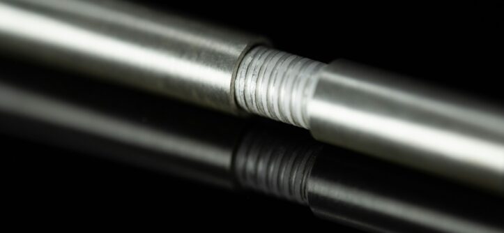 Metal rod with a threaded section reflecting on a black surface