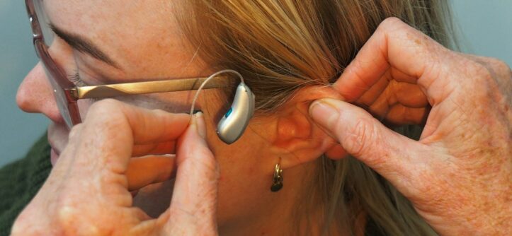 Woman having a receiver-in-canal hearing aid fitted, as part of checking comfort and fit