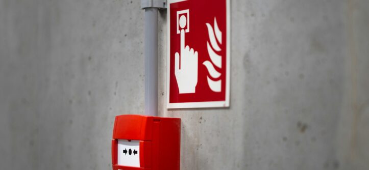 Red fire alarm button on an industrial concrete wall, ready to be triggered